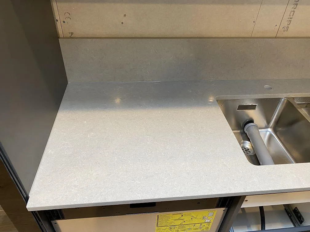 Köksbänkskiva i Technistone Noble Concrete Grey med underlimmad rostfri diskho och borrat blandarhål, under montering i Lund.