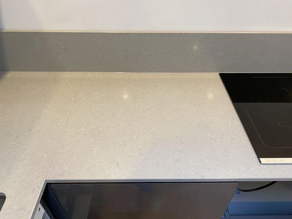 Bänkhörn med uppvikt grå stänkkant i Technistone Noble Concrete Grey och underlimmad rostfri diskho i ett kök i Lund.