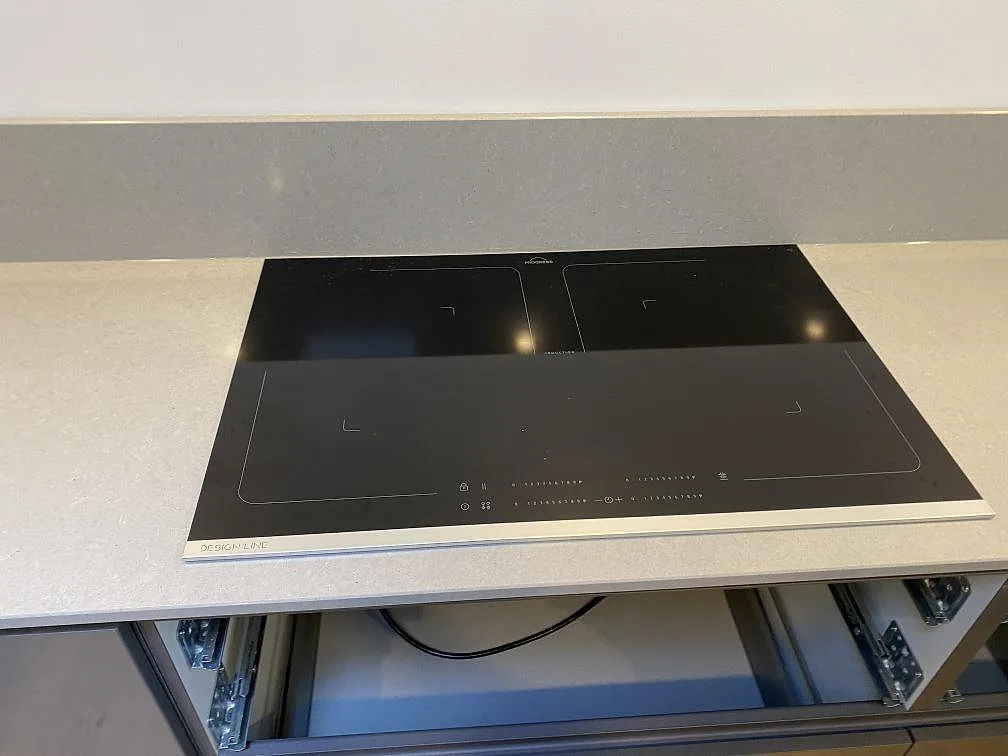 Polerad bänkskiva i Technistone Noble Concrete Grey med infälld svart induktionshäll, sedd uppifrån i ett kök i Lund.