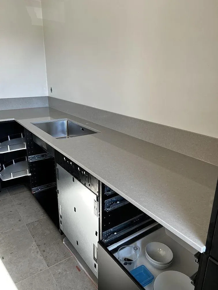 Köksö i grå Technistone Noble Concrete Grey kvartskomposit, polerad, under montering i ett kök i Lund.