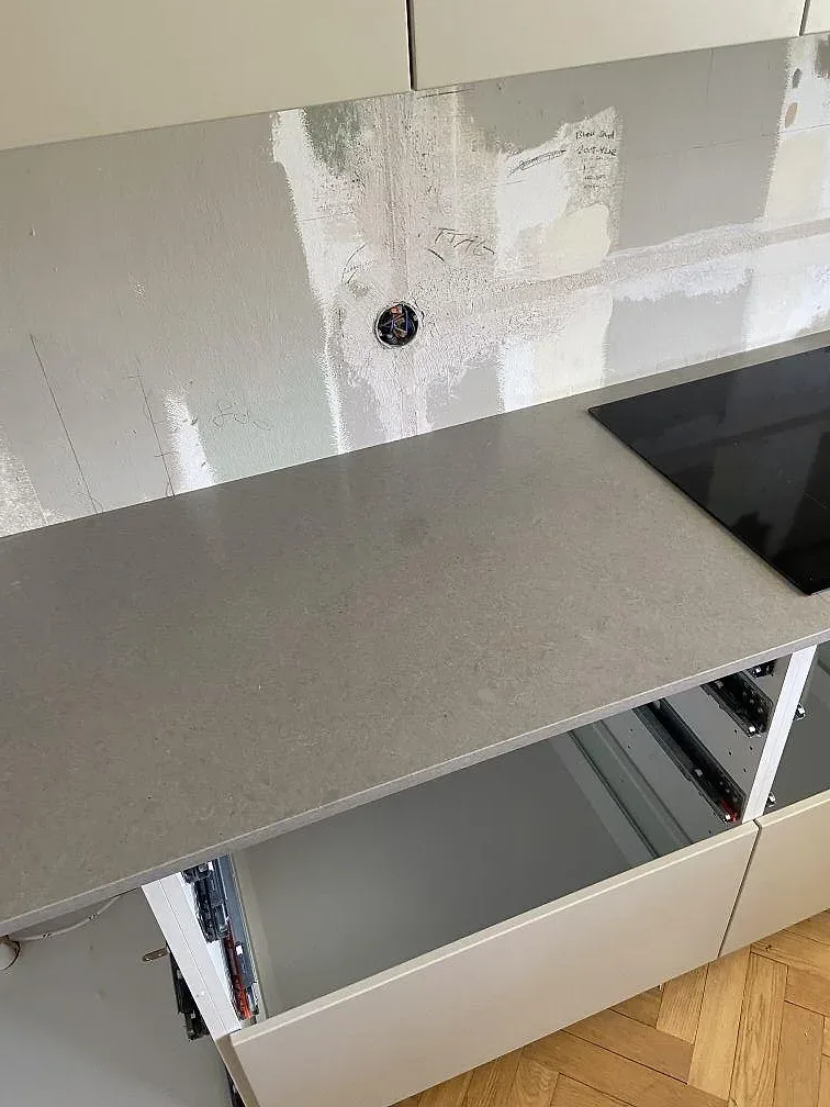 Köksbänkskiva i matt Technistone Noble Concrete Grey med svart häll och öppen köksstomme i ett kök i Malmö.