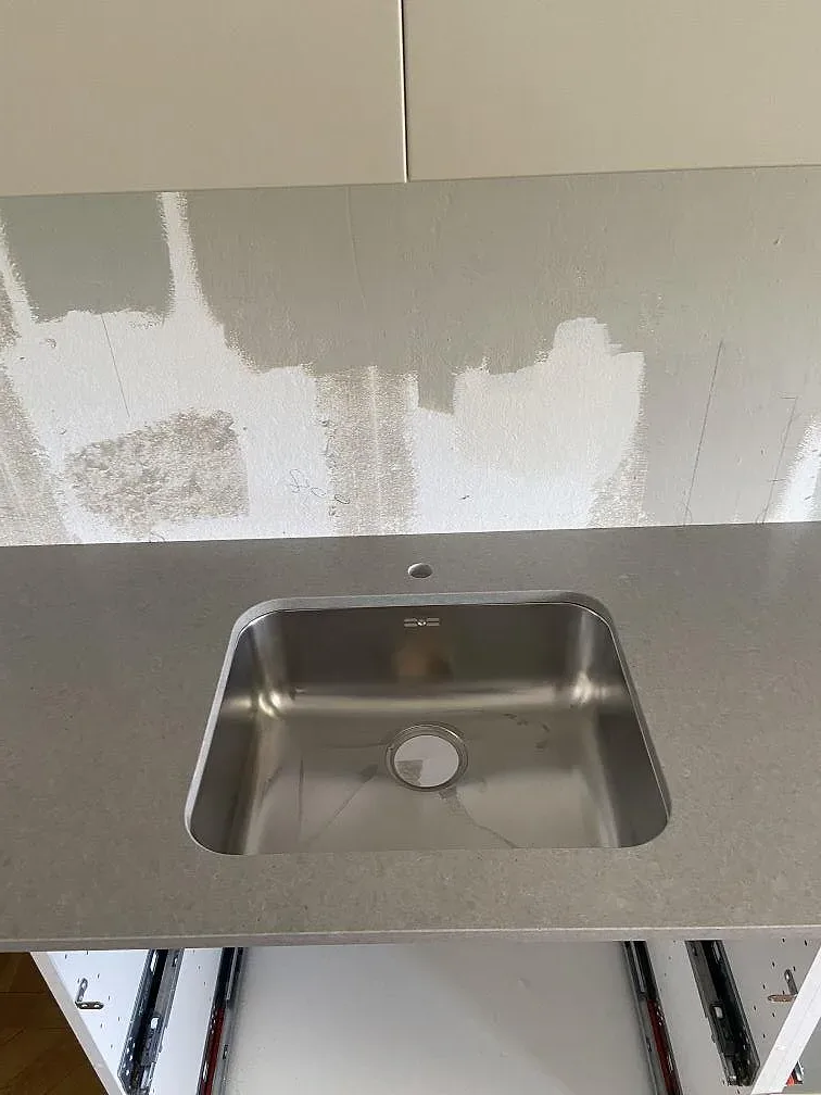 Närbild på underlimmad rostfri diskho i köksbänkskiva av matt Technistone Noble Concrete Grey i Malmö.