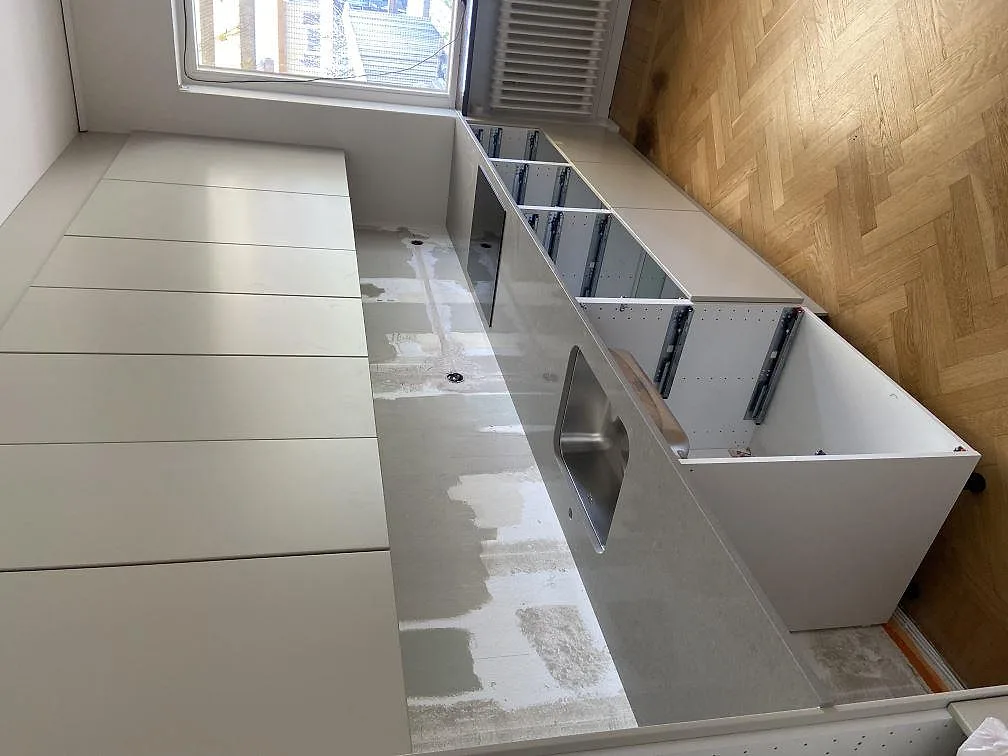 Detaljbild av monterad köksbänkskiva i grå Technistone Noble Concrete Grey, matt kvartskomposit, mot vägg i Malmö.
