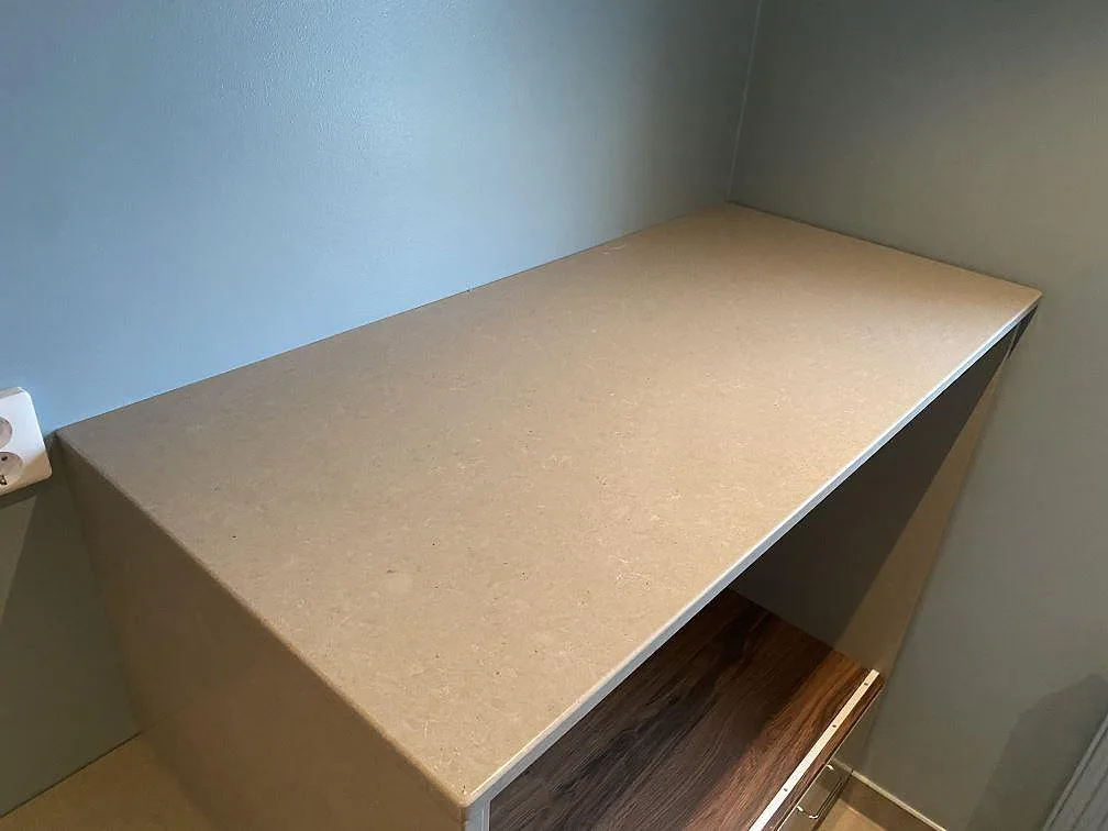 Närbild på polerad Technistone Noble Concrete Grey som ljusgrå kvartskomposit på en högre bänkdel i Malmö.
