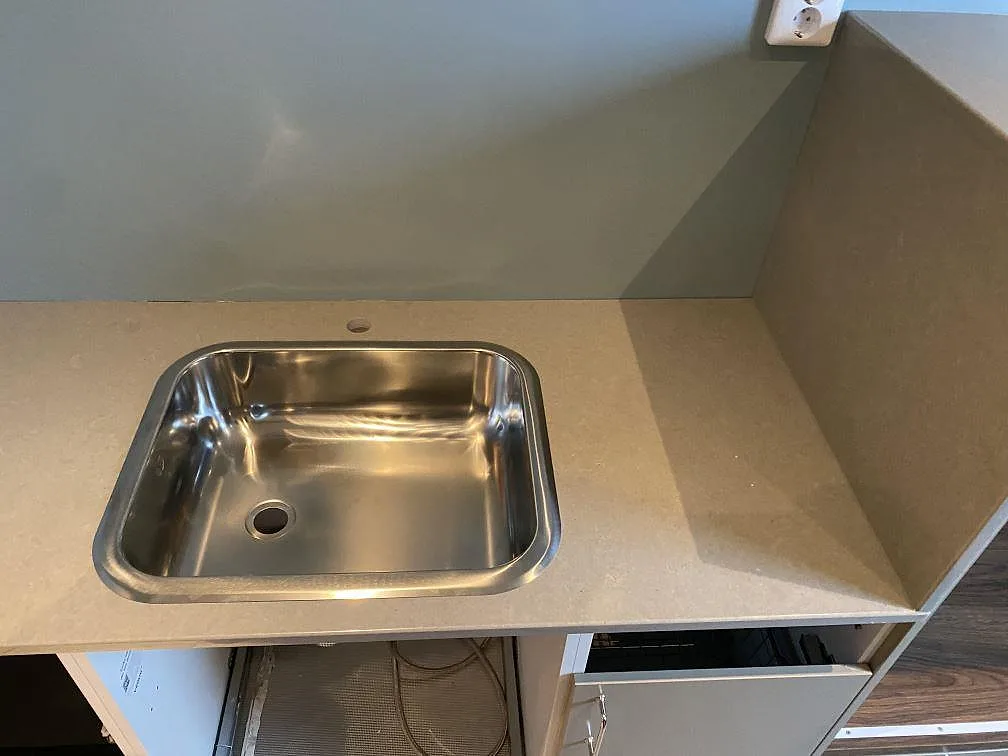 Detalj av köksbänkskiva i Technistone Noble Concrete Grey, polerad, med rostfri diskho och öppen stomme i Malmö.