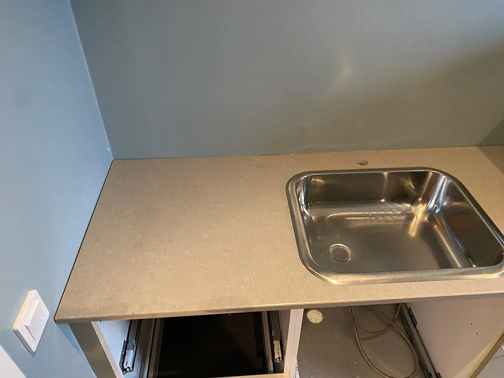 Ljusgrå köksbänkskiva i Technistone Noble Concrete Grey, polerad, med diskho och öppna stommar i Malmö.