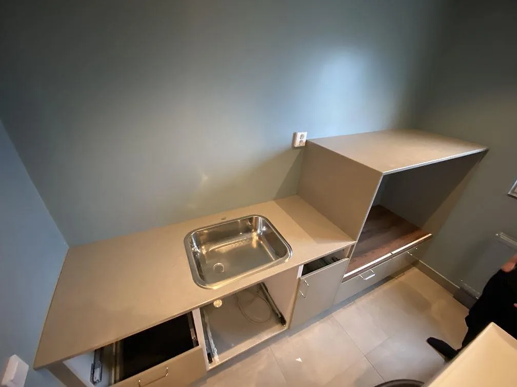 Köksbänkskiva i Technistone Noble Concrete Grey, polerad betongton, med underlimmad rostfri diskho och inklätt skåpparti i ett kök under montering i Malmö.