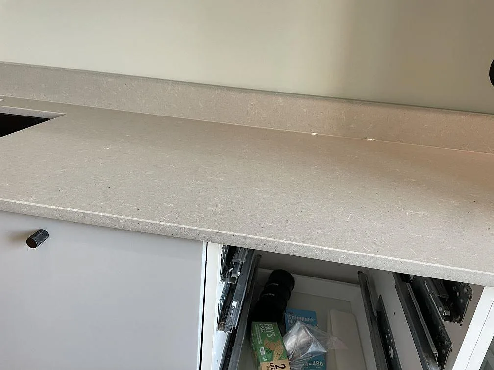 Rak arbetsyta i polerad Technistone Noble Concrete Grey med ljusgrå kvartskomposit, stänkkant och öppna köksstommar under montering i Malmö.
