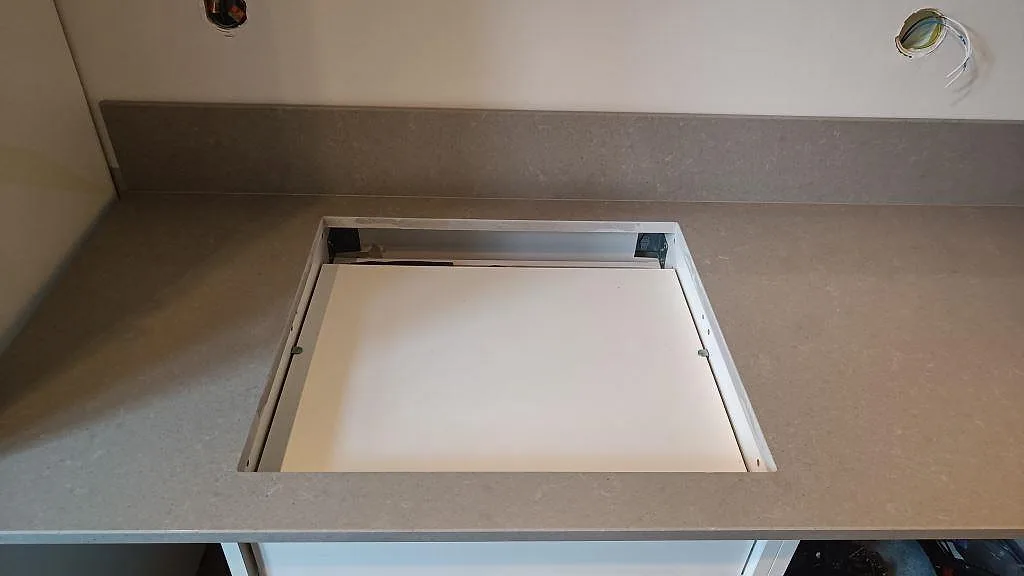 Närbild på hällöppning och grå polerad Technistone Noble Concrete Grey köksbänkskiva med stänkskydd i Malmö.