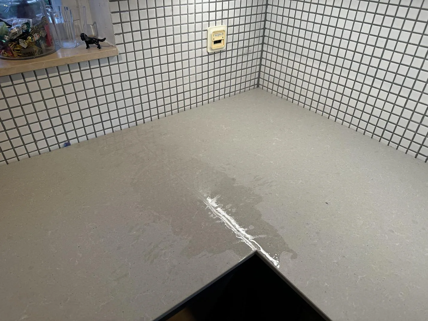 Hörnparti av matt Technistone Noble Concrete Grey köksbänkskiva med ljusgrå betongkänsla och mosaikkakel i Malmö.