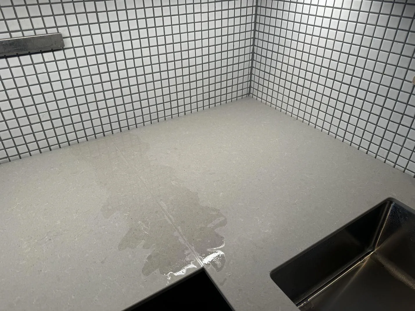 Matt grå Technistone Noble Concrete Grey köksbänkskiva vid diskhozonen och mosaikkakel i ett kök i Malmö.