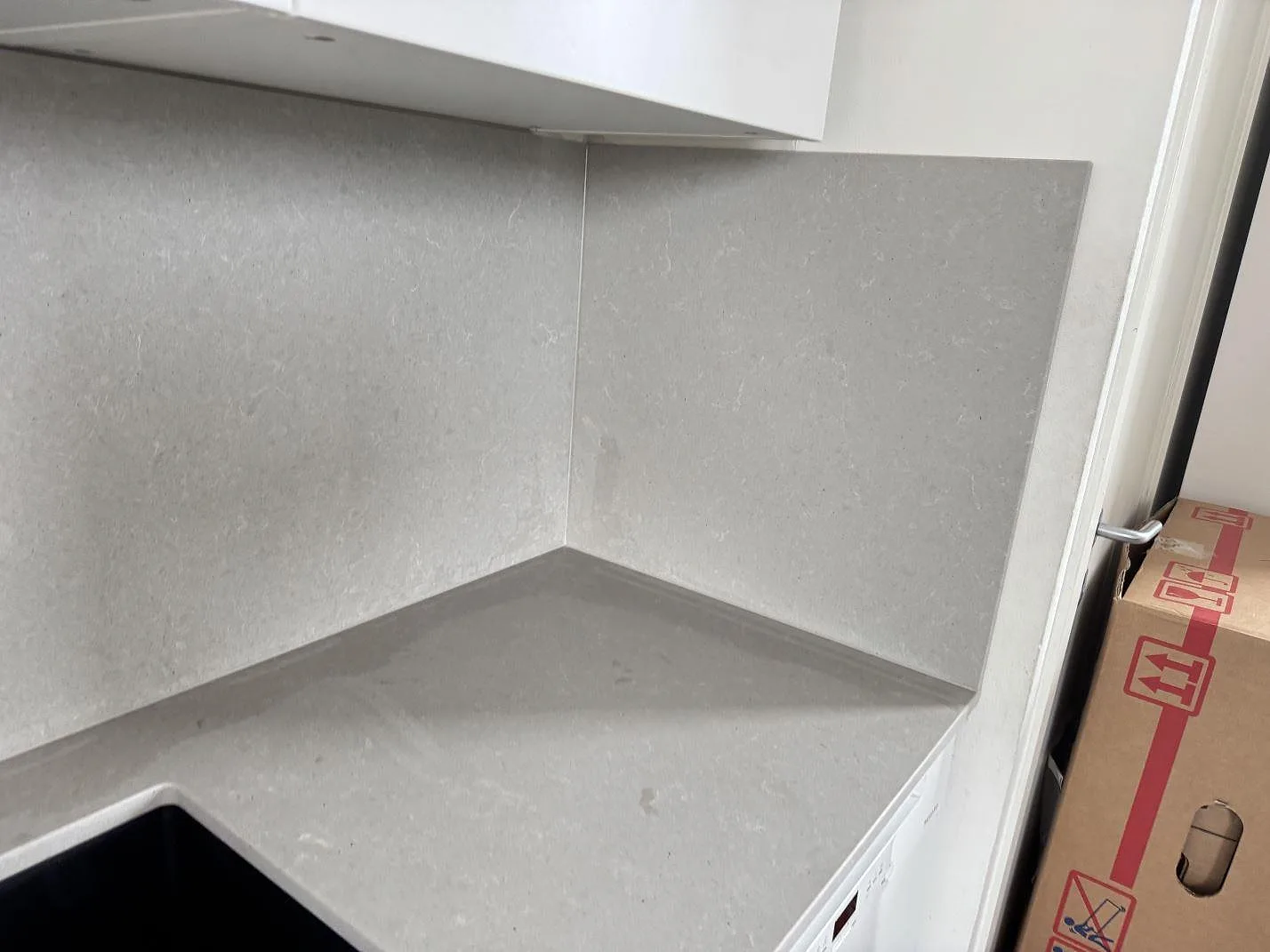 Höger avslutning med köksbänkskiva och stänkskydd i matt Technistone Noble Concrete Grey monterat mot vägg i Malmö.