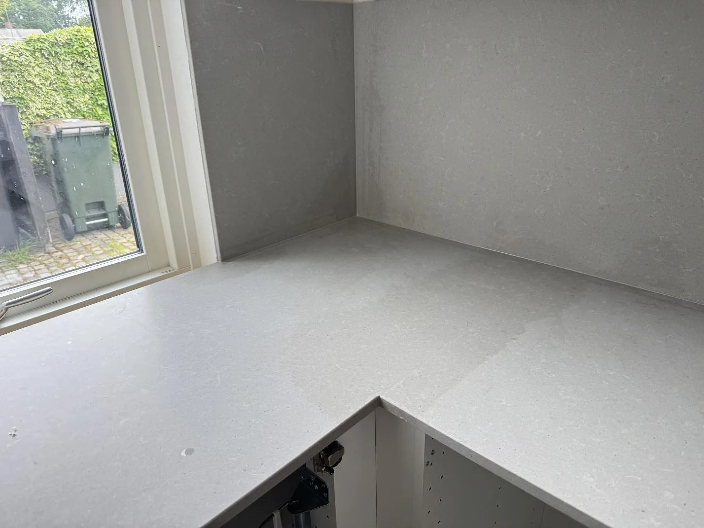 L-formad köksbänkskiva vid fönster i matt Technistone Noble Concrete Grey med matchande väggskivor i Malmö.