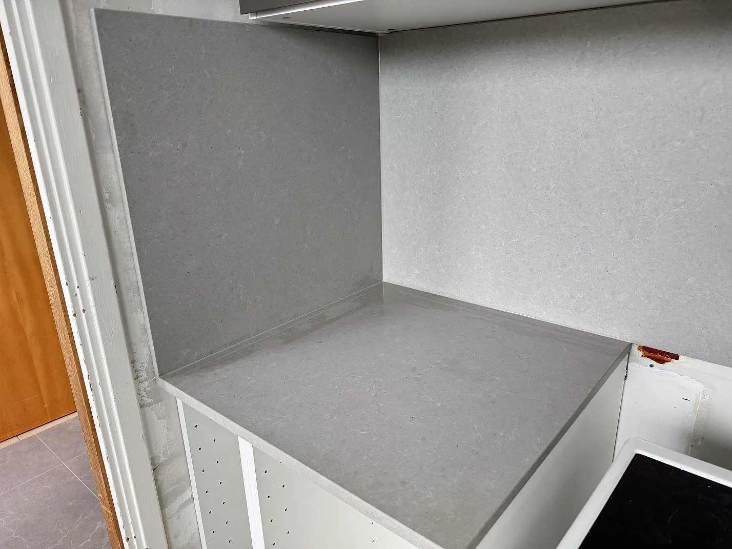 Hörnvy av köksbänkskiva och stänkskydd i matt Technistone Noble Concrete Grey, grå kvartskomposit, i ett kök i Malmö.