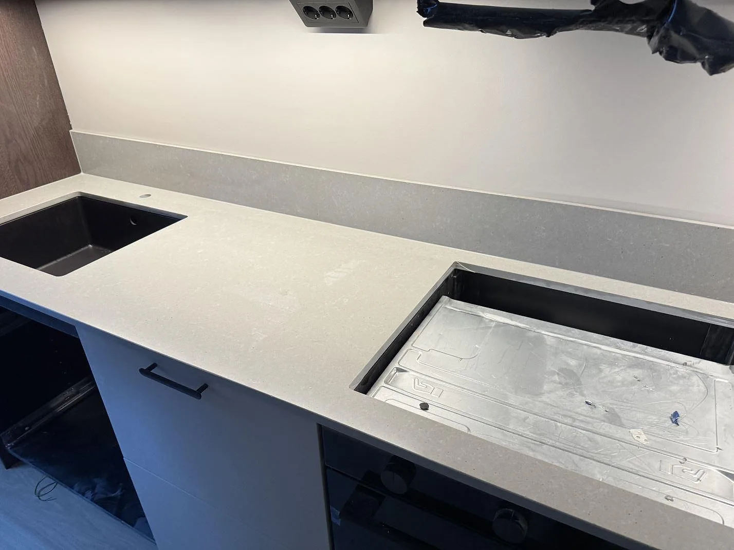 Köksbänkskiva i grå Technistone Noble Concrete Grey med betongliknande yta, underlimmad svart diskho och plats för en infälld häll längs en rak köksbänk i Malmö.