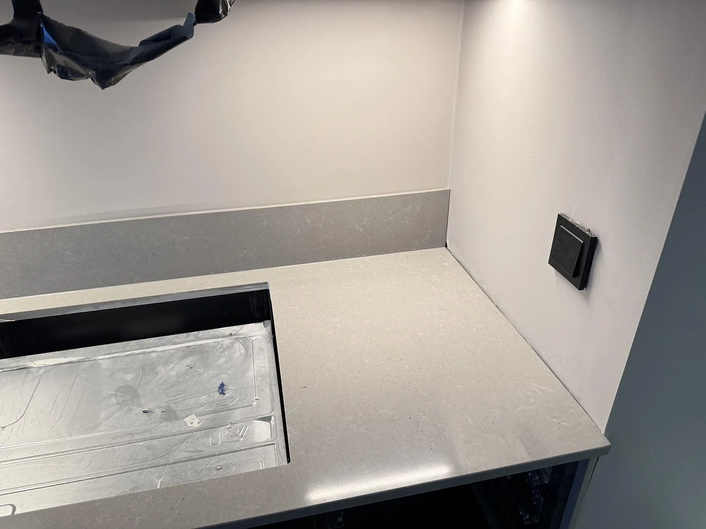 Närbild på köksbänkskiva i Technistone Noble Concrete Grey med uppvikt grå stänkkant och urtag för häll i ett kök i Malmö under montering.