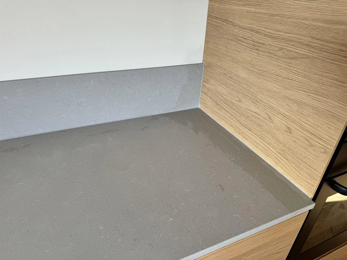 Grå matt Technistone Noble Concrete Grey bänkskiva med stänkskydd mot vägg och träinredning i ett kök i Mölndal.