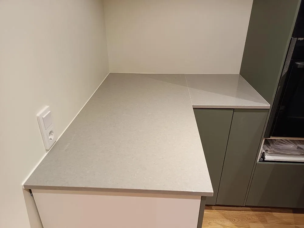 L-format hörn med köksbänkskiva i polerad Technistone Noble Concrete Grey, grå kvartskomposit med betongliknande yta, i Motala.