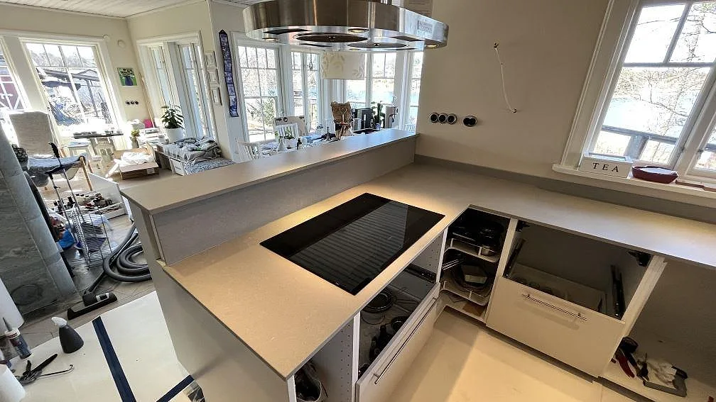 Hällzon i Technistone Noble Concrete Grey, matt grå kvartskomposit, med uppvikt stänkkant i ett kök i Norrby.