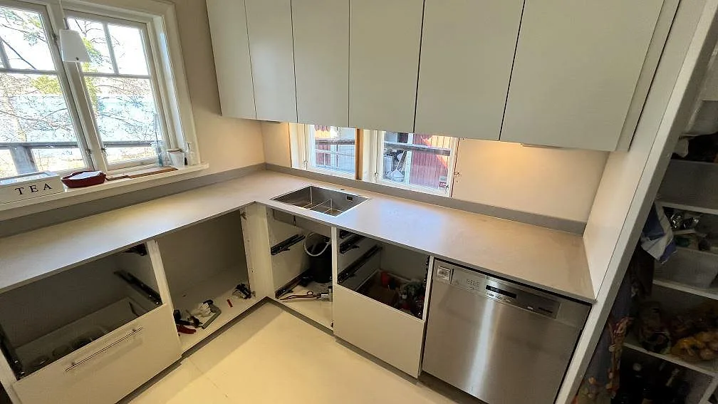 Köksbänkskiva i matt Technistone Noble Concrete Grey vid fönster och diskho, med låg stänkkant i Norrby.