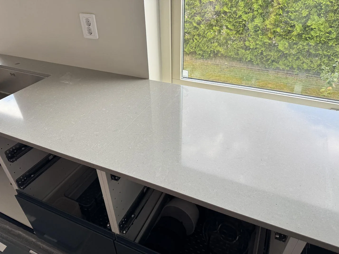Ljusgrå köksbänkskiva i polerad Technistone Noble Concrete Grey vid fönster och vägg i Svalöv.
