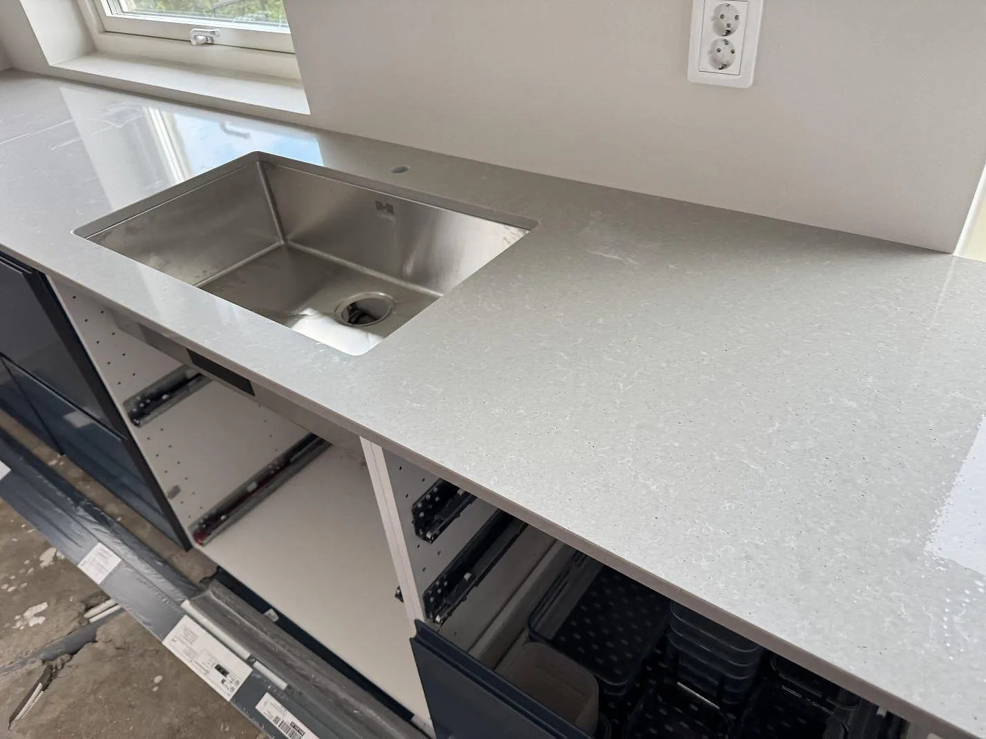 Polerad köksbänkskiva i Technistone Noble Concrete Grey med rostfri diskho och öppen köksstomme i Svalöv.