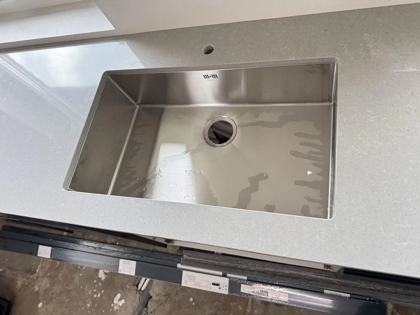 Närbild på rostfri diskho i en polerad bänkskiva av Technistone Noble Concrete Grey i ett kök i Svalöv.
