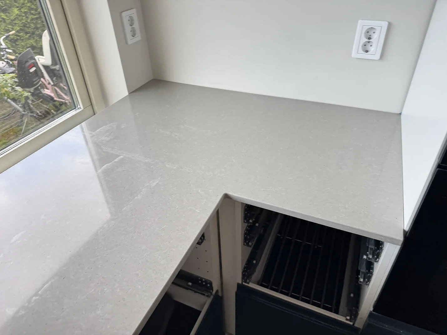 L-formad köksbänkskiva i polerad Technistone Noble Concrete Grey med öppen köksstomme i Svalöv.