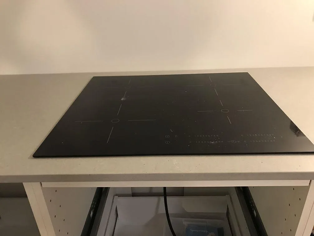 Induktionshäll nedsänkt i grå köksbänkskiva av Technistone Noble Concrete Grey i ett kök i Svedala.