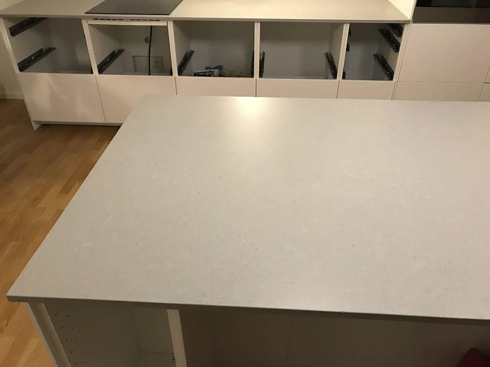 Köksö och bänkrad i Technistone Noble Concrete Grey med induktionshäll och öppna stommar i ett kök i Svedala.