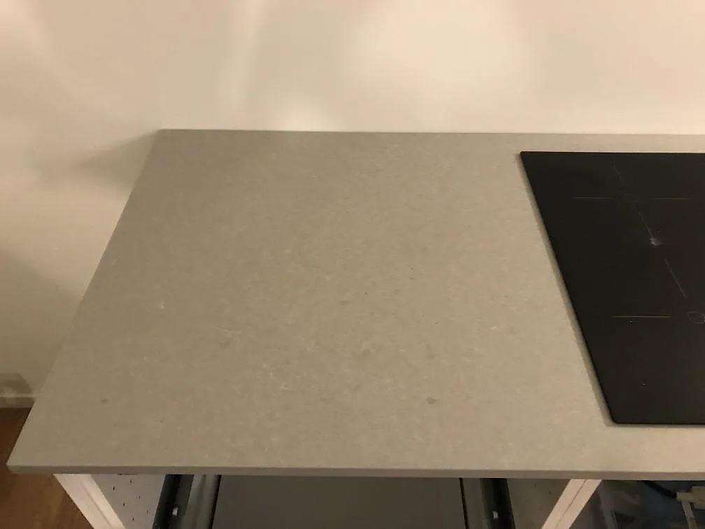 Bänkskiva i matt grå Technistone Noble Concrete Grey med infälld induktionshäll i ett kök i Svedala.