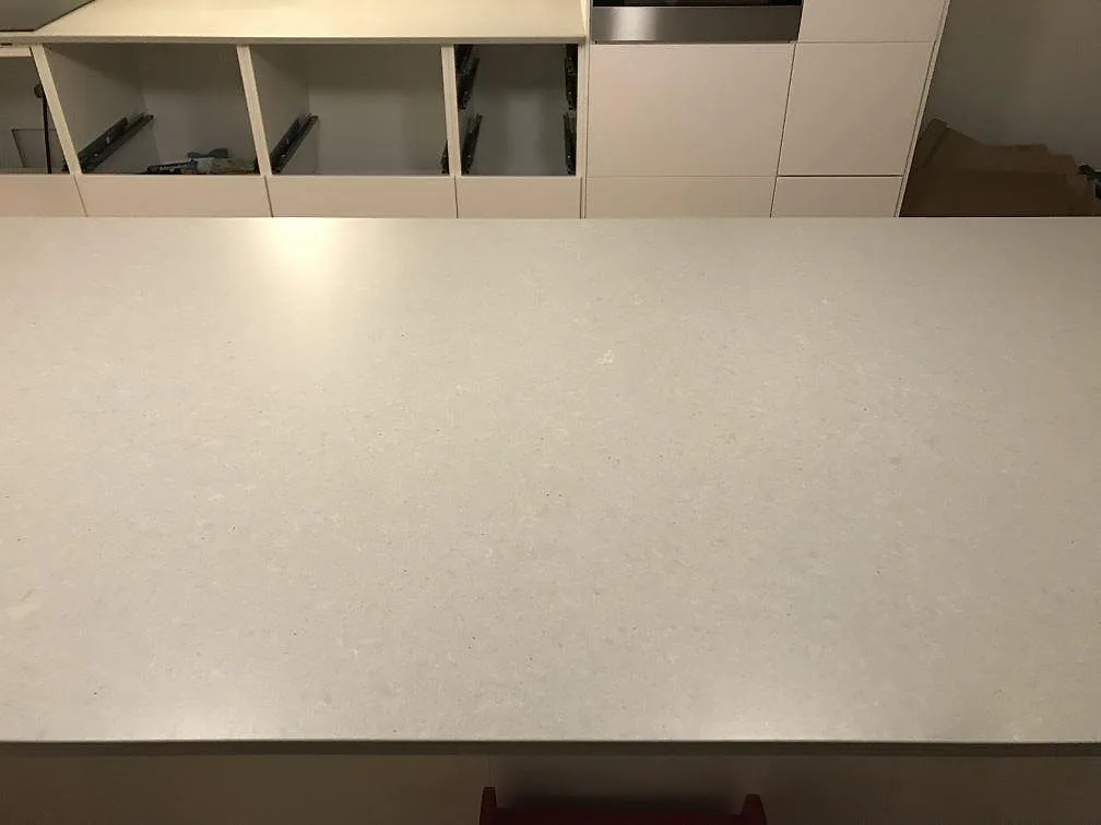 Stor köksö i matt grå Technistone Noble Concrete Grey komposit i ett kök under montering i Svedala.