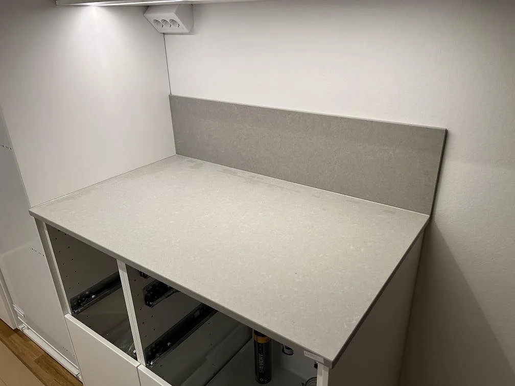 Närbild på matt Technistone Noble Concrete Grey som köksbänkskiva med lågt stänkskydd och öppna stommar i Täby.