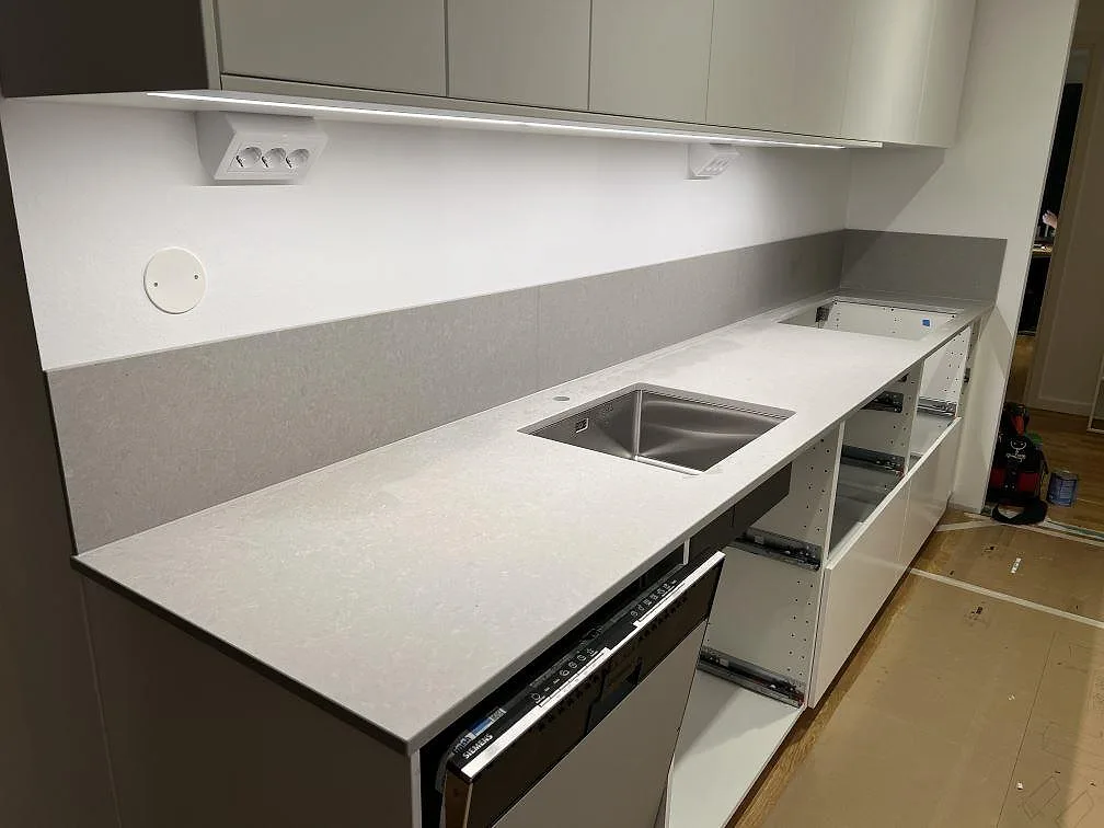 Matt kompositbänkskiva i Technistone Noble Concrete Grey med diskho och stänkskydd under montering i Täby.