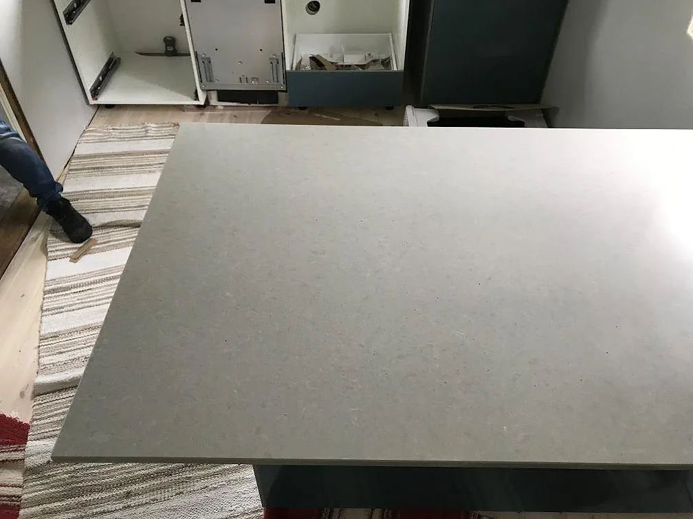Polerad grå Technistone Noble Concrete Grey bänkskiva sedd uppifrån över blå köksstommar i ett kök i Träslövsläge.