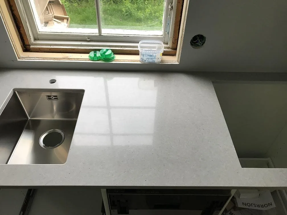 Grå Technistone Noble Concrete Grey köksbänkskiva med underlimmad rostfri diskho och ett andra förberett hourtag i ett kök i Träslövsläge.
