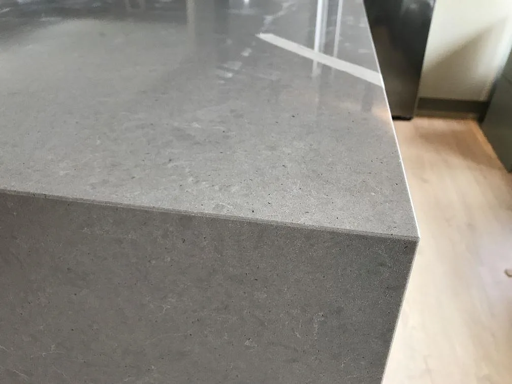 Närbild på den grå betongliknande Technistone Noble Concrete Grey med nedvikt vattenfallskant på köksön i Tygelsjö.