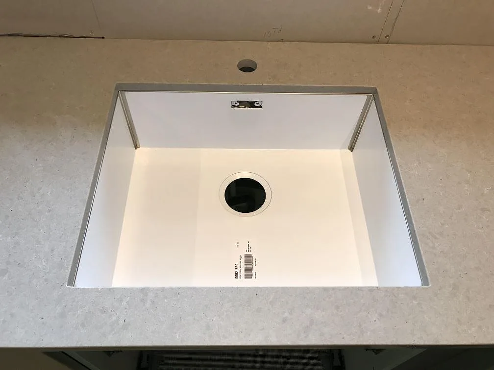 Polerad köksbänkskiva i Technistone Noble Concrete Grey sedd uppifrån med underlimmad diskho och kranhål i ett kök i Tygelsjö.