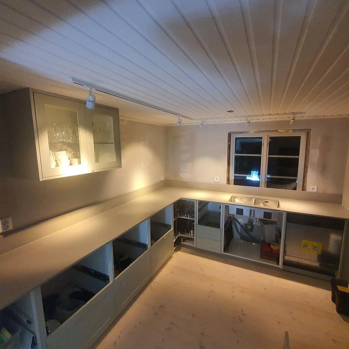 Köksbänkskiva i matt Technistone Noble Concrete Grey, grå kvartskomposit med låg stänkkant och arbetsyta vid fönster i ett kök i Uppsala.