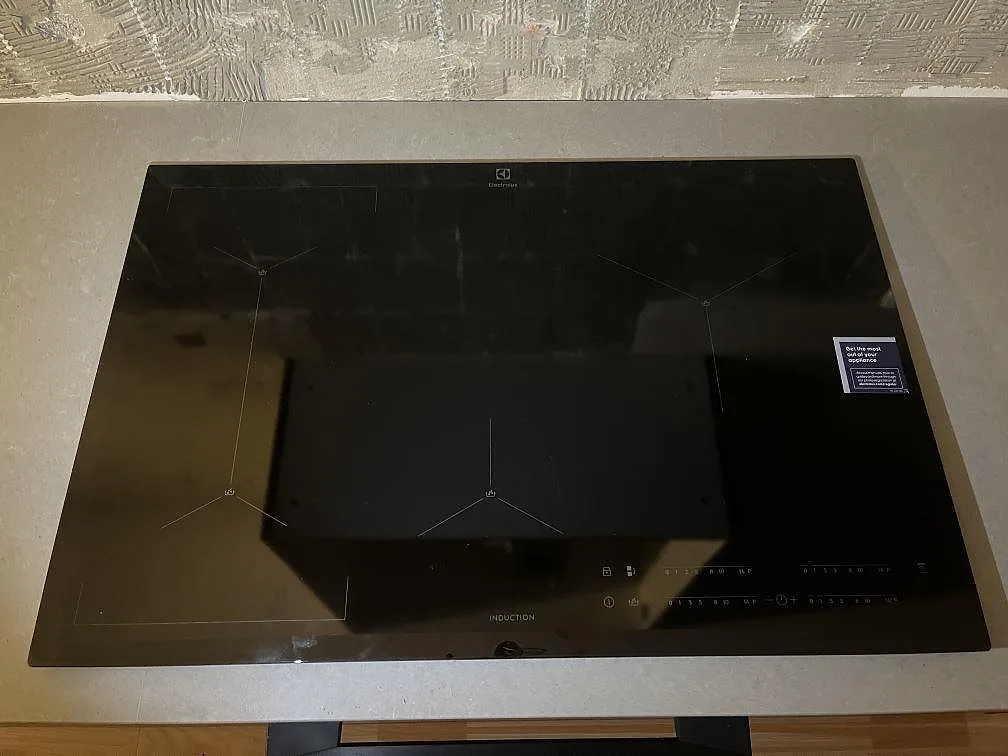 Närbild på svart induktionshäll infälld i polerad Technistone Noble Concrete Grey i ett kök i Västerås.