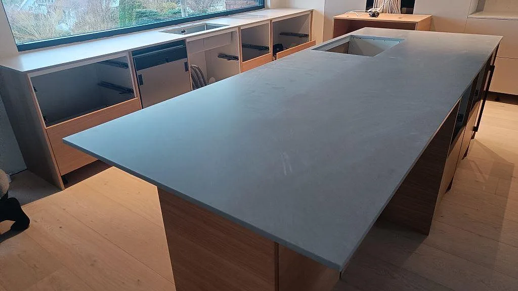 Närbild på matt köksö i Technistone Noble Concrete Grey med grå kvartskomposityta och öppning i ett kök i Västra Frölunda.