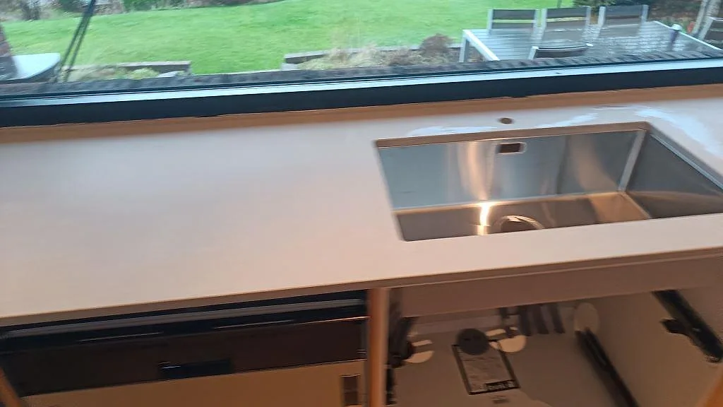 Vinklad vy över bänkskiva i matt Technistone Noble Concrete Grey med rostfri diskho och öppen köksstomme i Västra Frölunda.