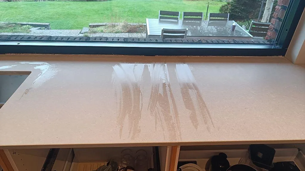 Ytdetalj av matt Technistone Noble Concrete Grey längs fönstret med ljus grå kvartskompositstruktur i Västra Frölunda.