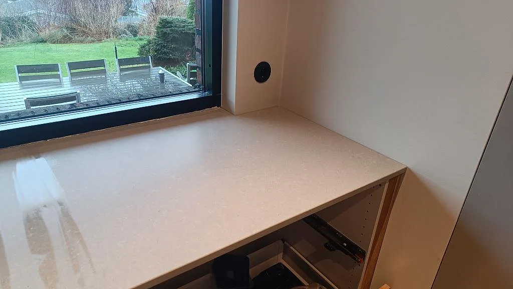 Hörnvy av matt Technistone Noble Concrete Grey på bänkraden vid fönstret i ett kök under montering i Västra Frölunda.