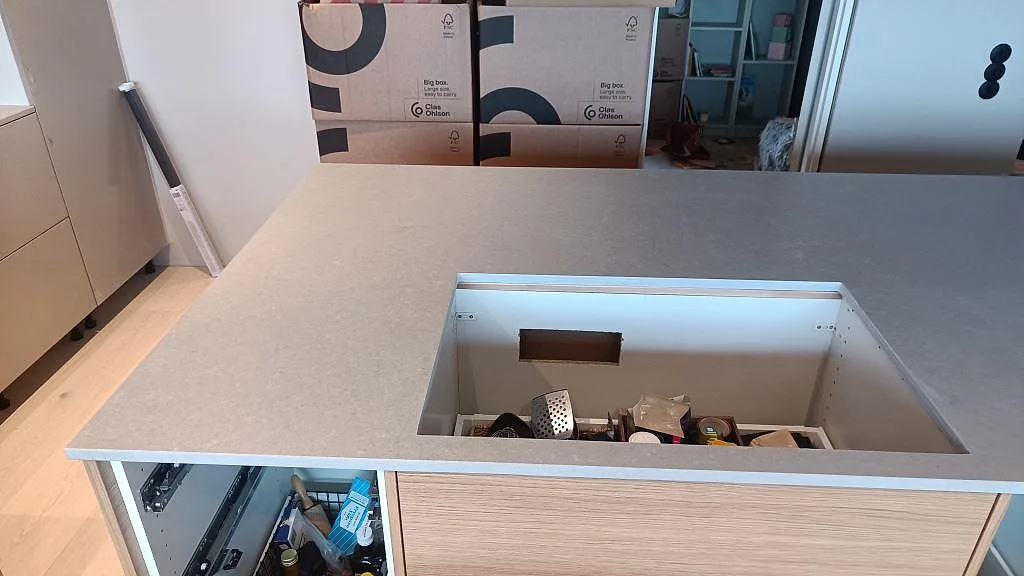 Köksö i matt Technistone Noble Concrete Grey med rektangulärt urtag och öppna trästommar under montering i Västra Frölunda.