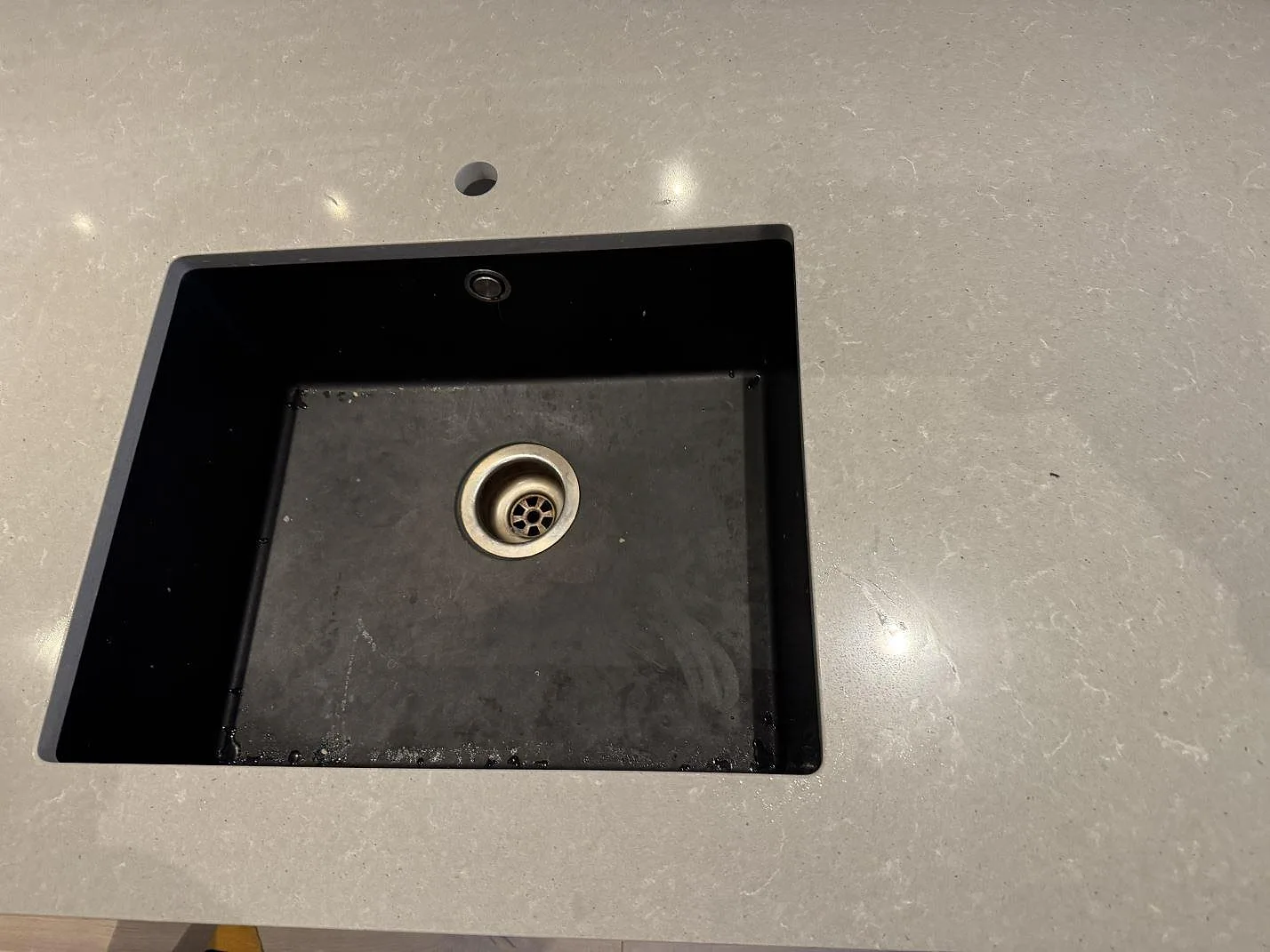 Detalj av mörk diskho i en polerad köksbänkskiva av Technistone Noble Concrete Grey, ljusgrå kvartskomposit i Västra Frölunda.
