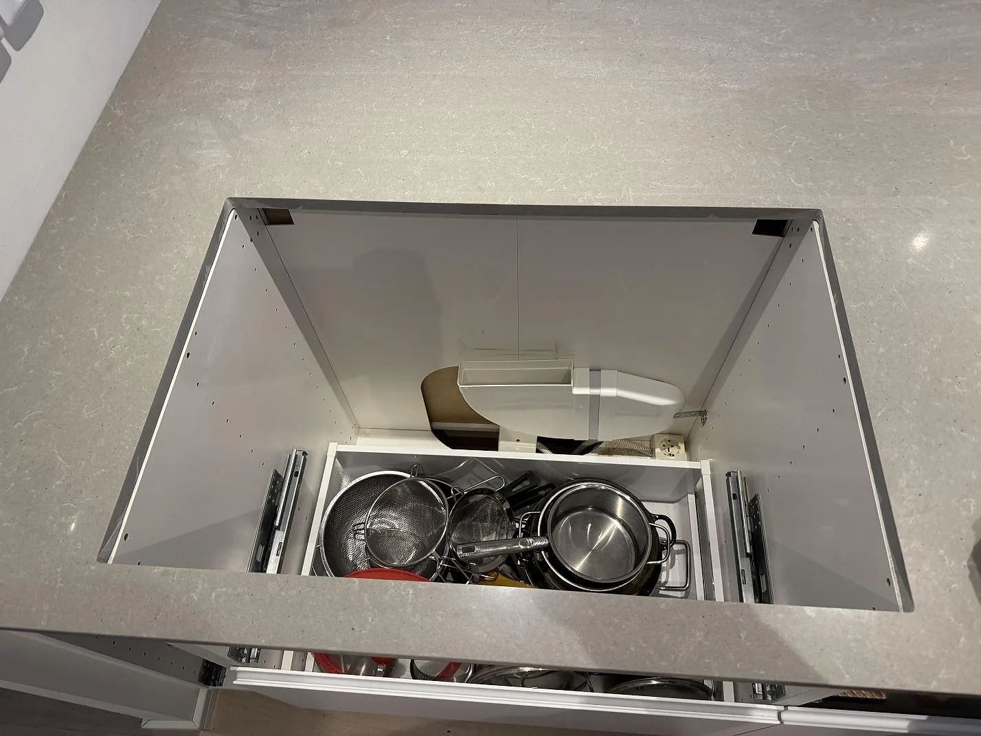 Detaljbild av köksbänkskiva i polerad Technistone Noble Concrete Grey över öppen skåpstomme i Västra Frölunda.
