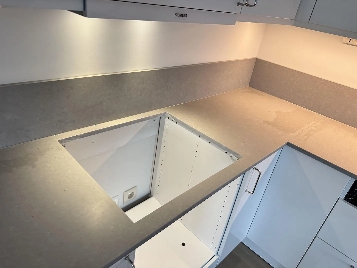 Köksbänkskiva i matt Technistone Noble Concrete Grey med urtag för ho över öppna stommar under montering i Varberg.