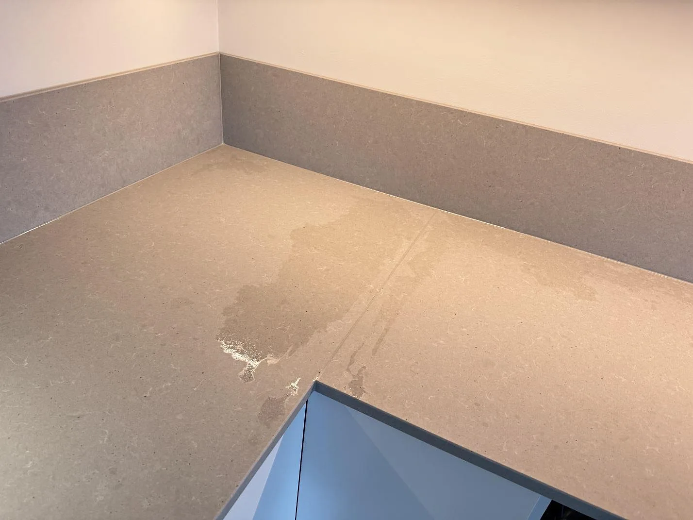 Ovanifrån av grå Technistone Noble Concrete Grey köksbänk med stänkkant och synlig skarv i ett kök i Varberg.