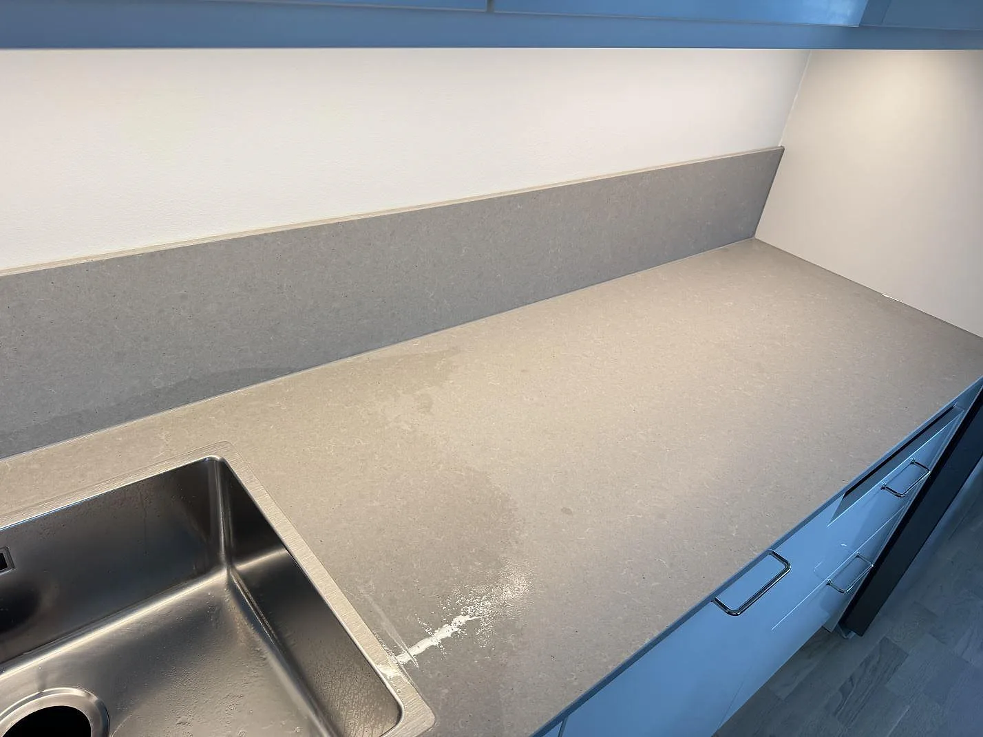Lång köksbänk i grå Technistone Noble Concrete Grey med underlimmad rostfri ho och låg stänkkant i ett kök i Varberg.